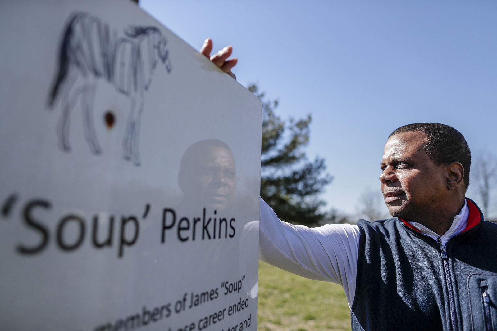 Leon Nichols, 51, co-founder of Project to Preserve African-American Turf History, a group dedicated to educating people about the groundbreaking role of black equestrians and to preserving African Cemetery #2, stands next to a sign honoring James “Soup” Perkins at African Cemetery No. 2.